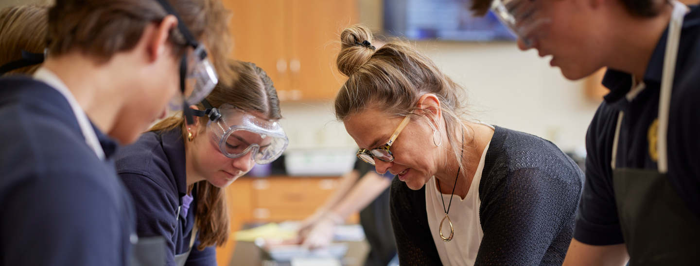 Science teacher working with students in lab